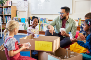 Teacher smiling teaching students to recycle in classroom
